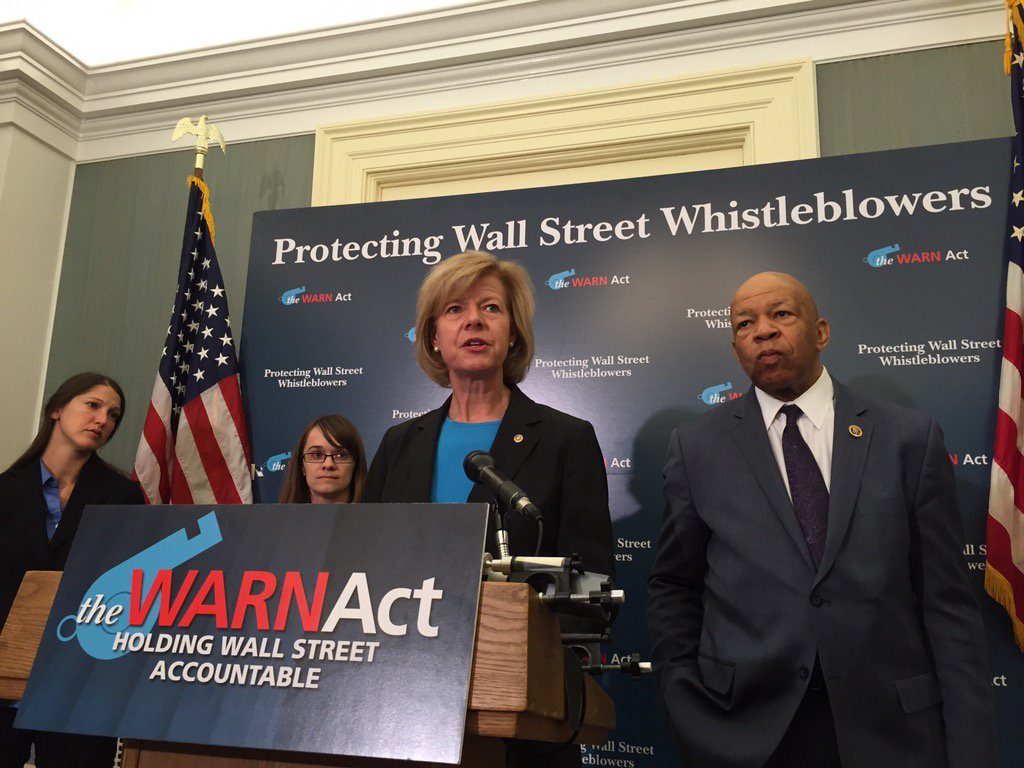 Sen. Tammy Baldwin speaks at a podium to introduce the WARN Act to enhance whistleblower protections.